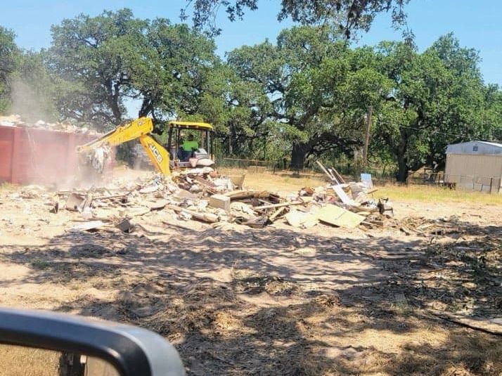 Bobcat loading demolished mobile home debris into a large dumpster