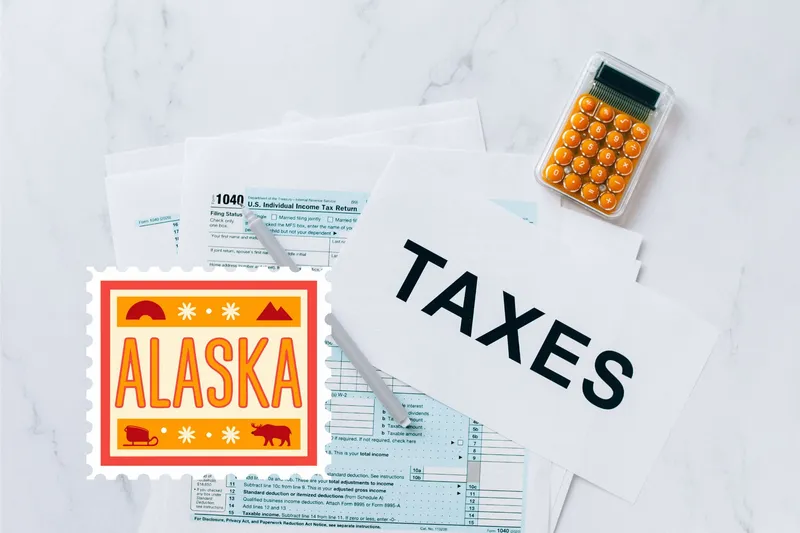 A capital gains calculator sits next to tax forms, a paper with the word 'TAXES', and an Alaska state logo on a white marble surface.