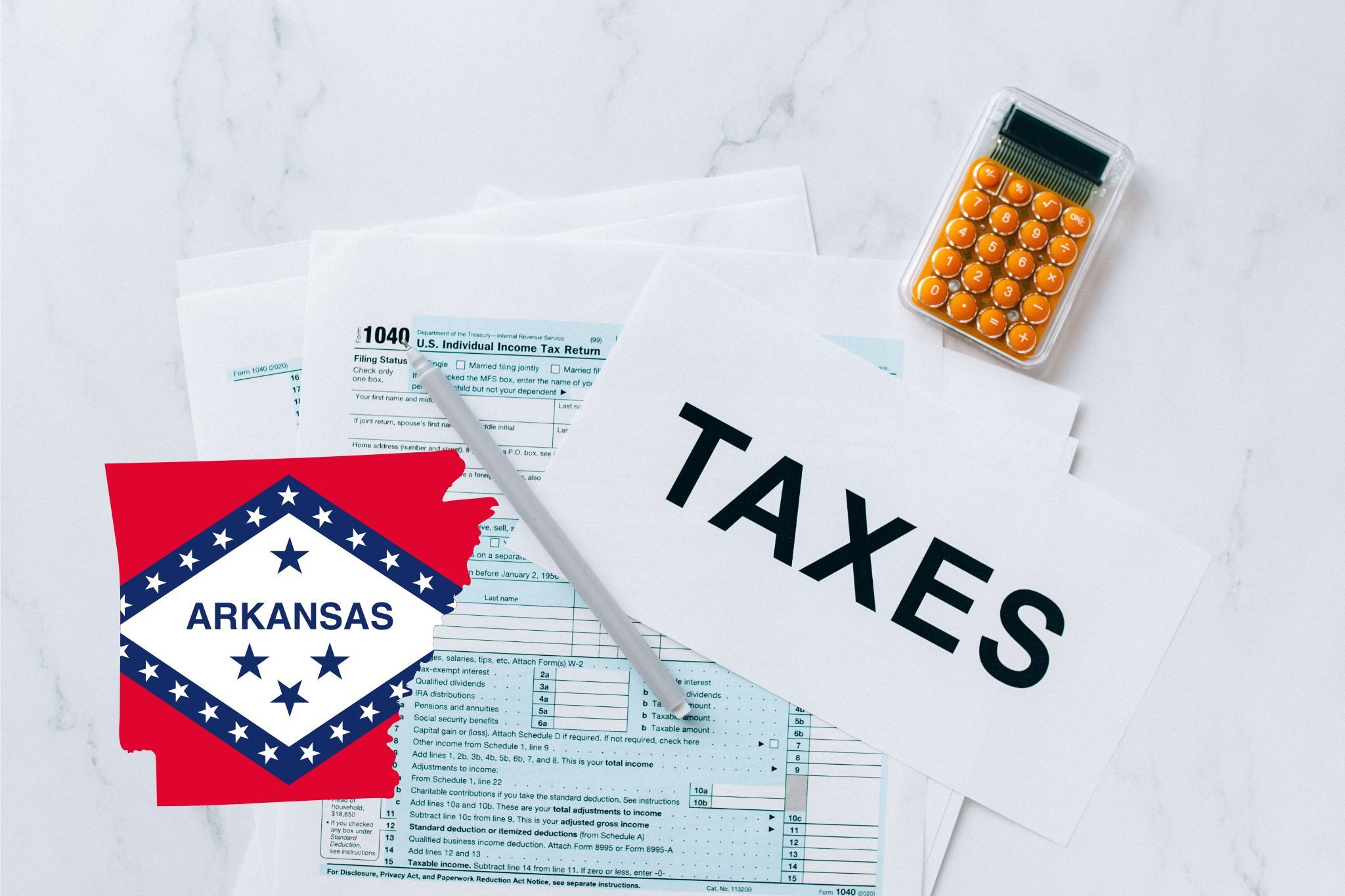 A capital gains calculator sits next to tax forms, a paper with the word 'TAXES', and an Arkansas state logo on a white marble surface.
