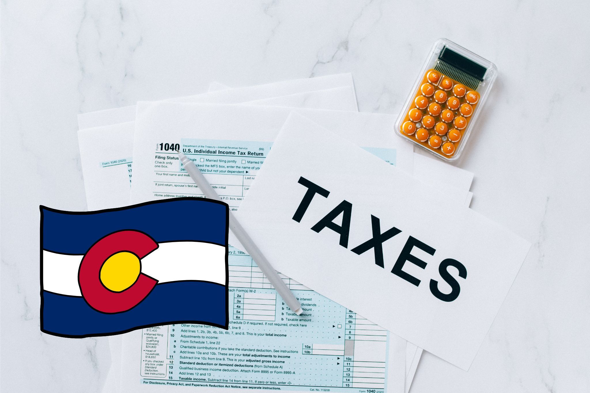 A capital gains calculator sits next to tax forms, a paper with the word 'TAXES', and an Colorado state logo on a white marble surface.