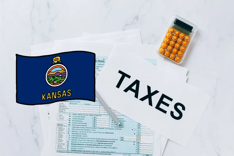 A capital gains calculator sits next to tax forms, a paper with the word 'TAXES', and an Kansas state logo on a white marble surface.