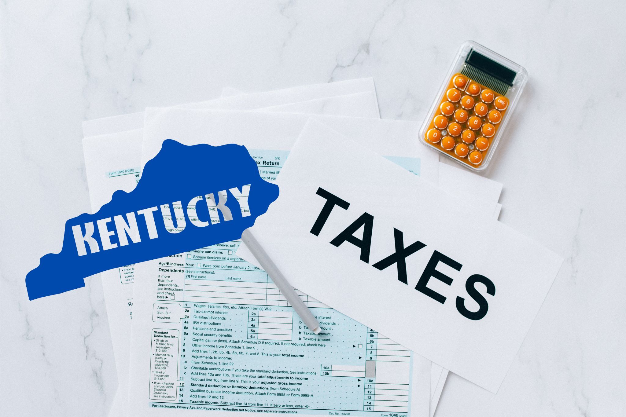 A capital gains calculator sits next to tax forms, a paper with the word 'TAXES', and an Kentucky state logo on a white marble surface.