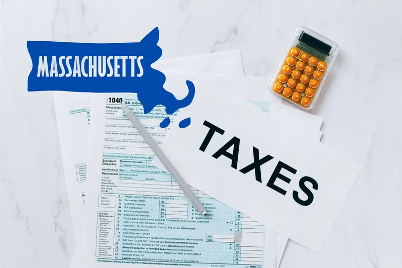 A capital gains calculator sits next to tax forms, a paper with the word 'TAXES', and an Massachusetts state logo on a white marble surface.