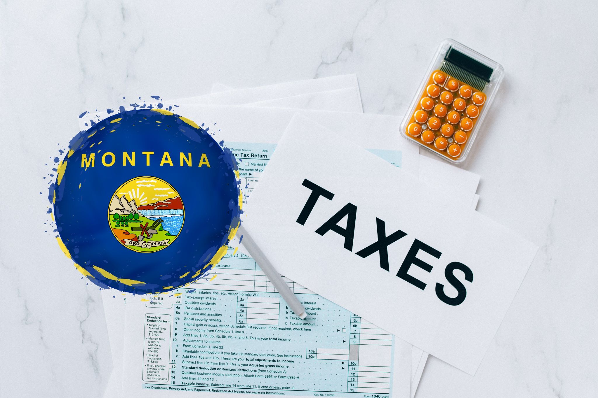 A capital gains calculator sits next to tax forms, a paper with the word 'TAXES', and an Montana state logo on a white marble surface.