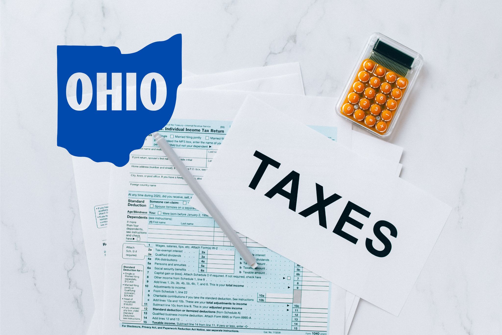 A capital gains calculator sits next to tax forms, a paper with the word 'TAXES', and an Ohio state logo on a white marble surface.