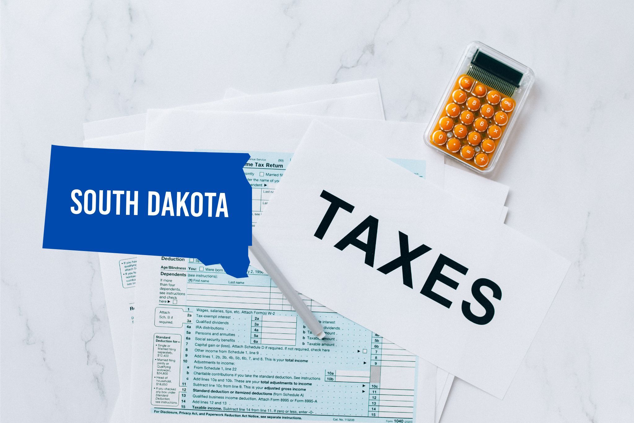 A capital gains calculator sits next to tax forms, a paper with the word 'TAXES', and an South Dakota state logo on a white marble surface.