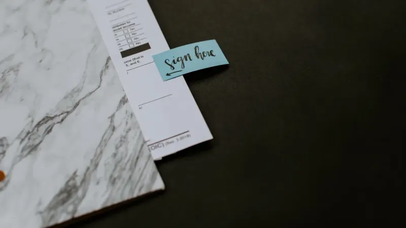 documents on a table with a sign here sticker