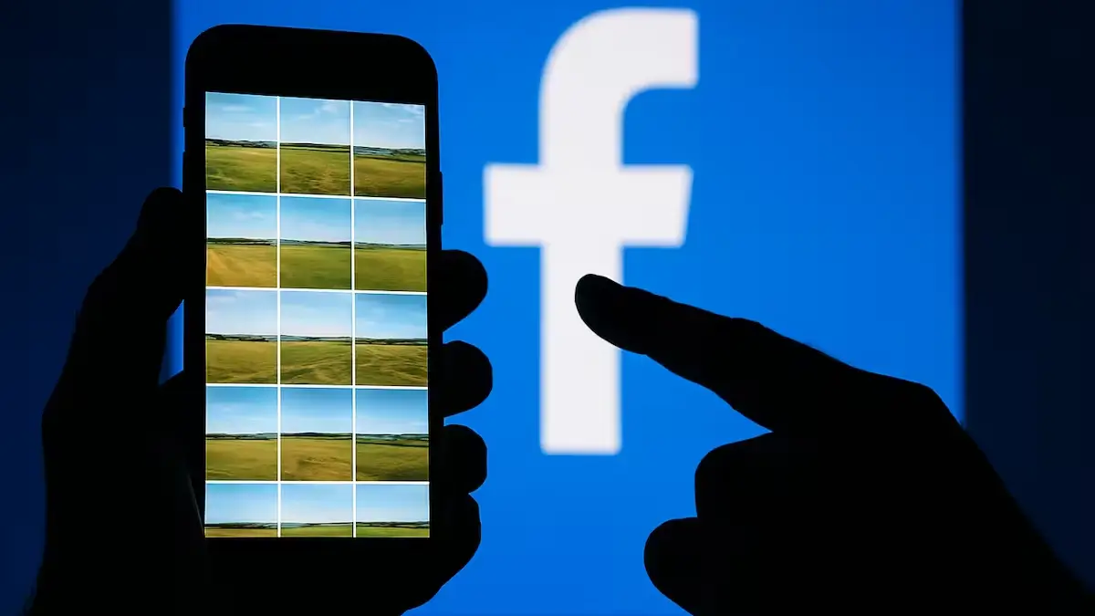 Hand holding smartphone in front of Facebook logo