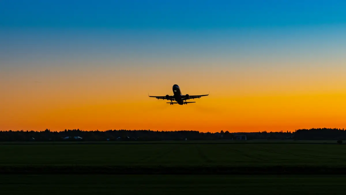 Selling out-of-state property: Airplane silhouette flies low over agricultural land during a vibrant sunset.